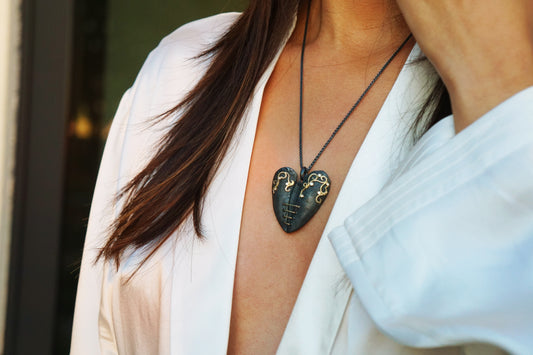 mended heart necklace oxidized silver with 18-karat gold and .07 ctw diamonds. Necklace worn on female with white robe